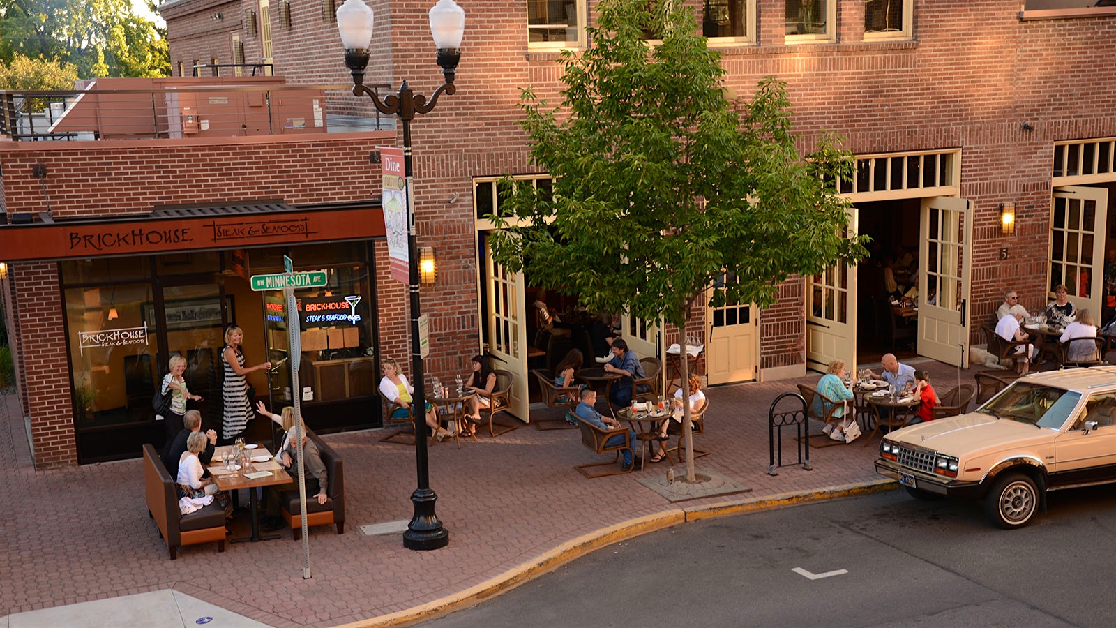 People dining outside of Brickhouse, a brick building that was formerly the historic firehall building, with large cream-colored, glass-paneled doors